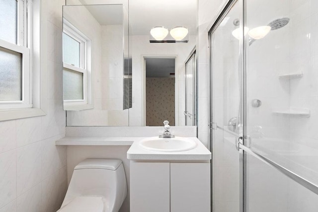 bathroom with toilet, a stall shower, vanity, and tile walls