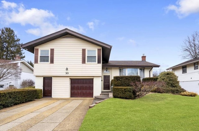 split level home featuring a garage, concrete driveway, a chimney, and a front lawn