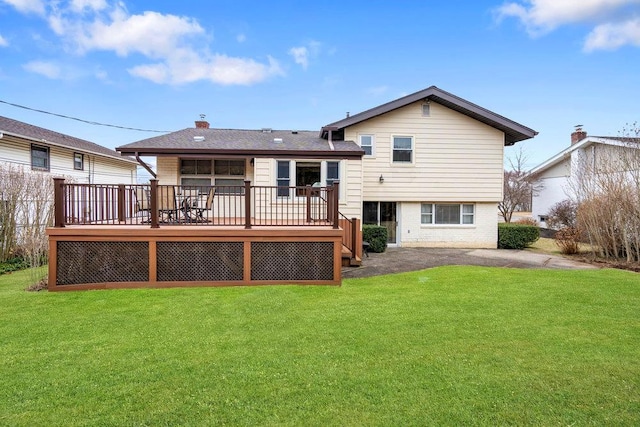 rear view of property featuring a deck, brick siding, a lawn, and a chimney