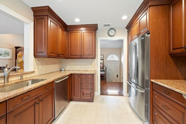 kitchen with visible vents, decorative backsplash, appliances with stainless steel finishes, a sink, and light stone countertops