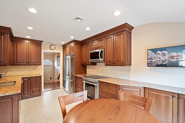 kitchen with light stone counters, light tile patterned floors, stainless steel appliances, tasteful backsplash, and visible vents