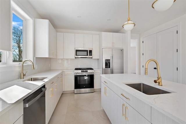 kitchen with sink, appliances with stainless steel finishes, white cabinetry, and decorative light fixtures