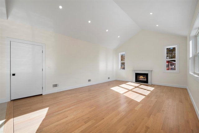 unfurnished living room with light wood-type flooring and high vaulted ceiling