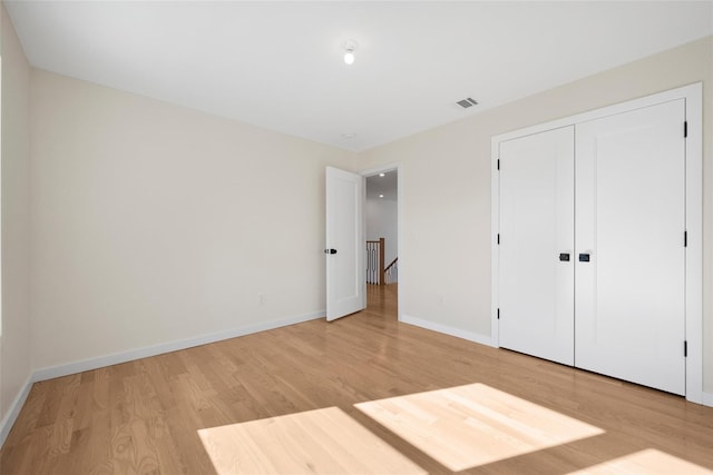 unfurnished bedroom with a closet and light hardwood / wood-style floors