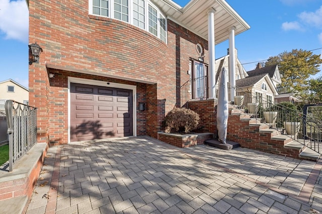 exterior space with a garage, fence, stairway, and brick siding