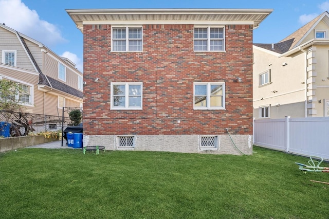 back of house featuring a yard, fence, and brick siding