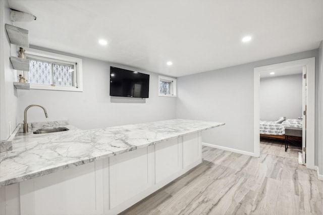 bar featuring baseboards, recessed lighting, a sink, and light wood-style floors