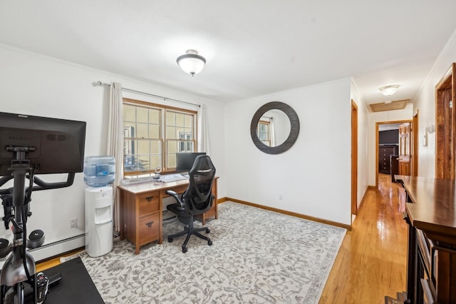 office space with light wood finished floors, a baseboard radiator, ornamental molding, attic access, and baseboards