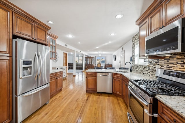 kitchen featuring stainless steel appliances, a sink, light wood-style flooring, and brown cabinets