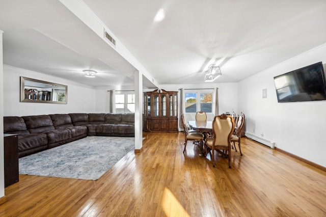 dining space featuring a baseboard radiator, visible vents, light wood-style flooring, and baseboards