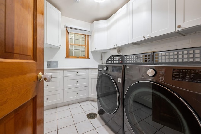 laundry room with cabinet space, light tile patterned floors, and independent washer and dryer