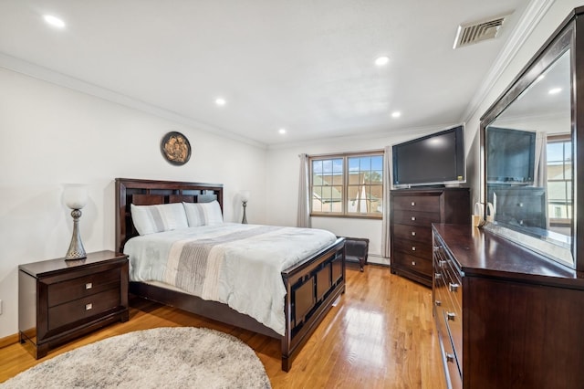 bedroom with ornamental molding, light wood-style flooring, and visible vents