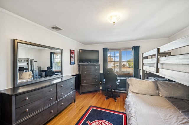 bedroom featuring light wood finished floors, visible vents, and crown molding