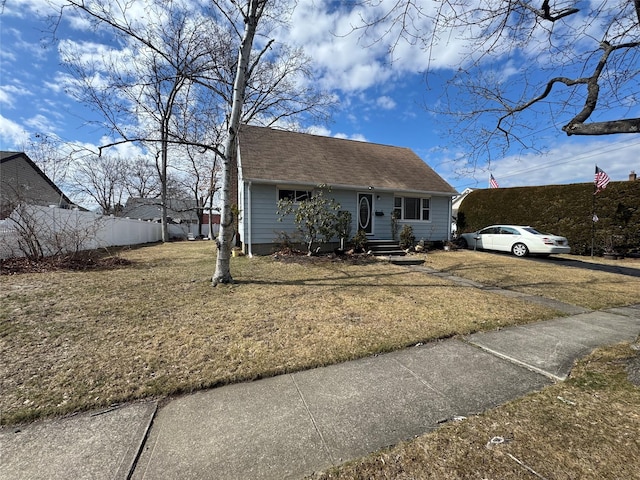 view of front of home featuring a front yard, fence, and a shingled roof