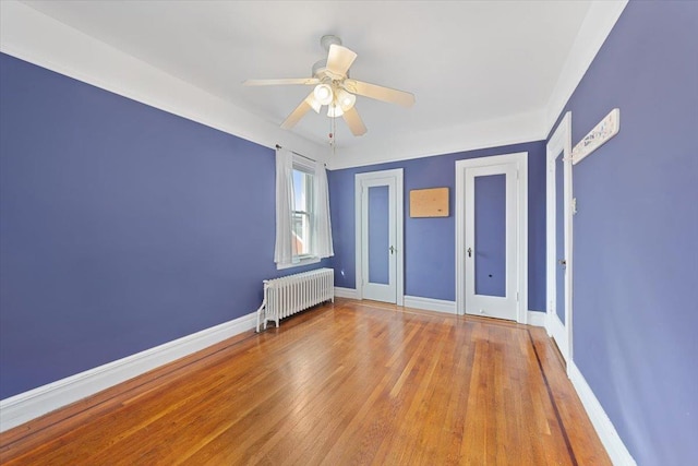 unfurnished bedroom featuring radiator, baseboards, ceiling fan, and light wood finished floors