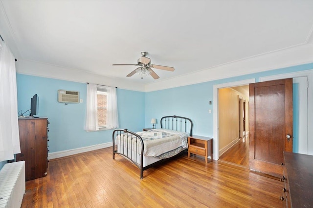 bedroom featuring wood finished floors, radiator heating unit, a wall mounted AC, and baseboards