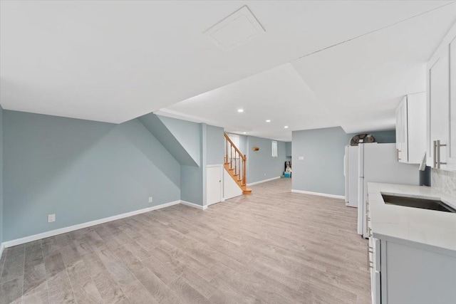 additional living space with recessed lighting, light wood-style floors, a sink, baseboards, and stairs