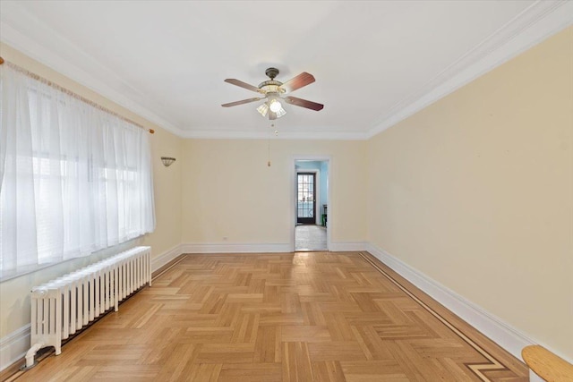 spare room with radiator, ceiling fan, baseboards, and crown molding