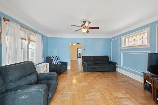 living room featuring ceiling fan, baseboards, a decorative wall, and crown molding