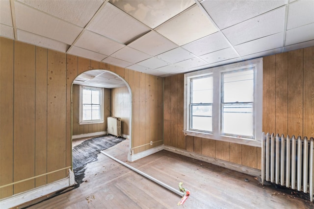 empty room featuring radiator heating unit and wooden walls