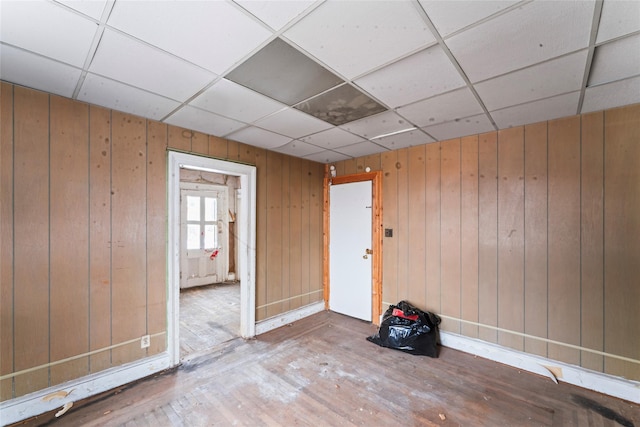 spare room with hardwood / wood-style flooring, a paneled ceiling, and wood walls