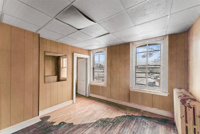 unfurnished room with radiator, hardwood / wood-style flooring, and wooden walls