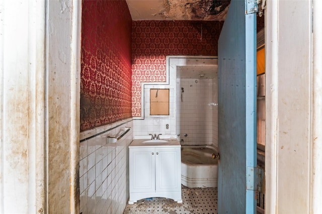 bathroom featuring vanity, a bathtub, and tile walls