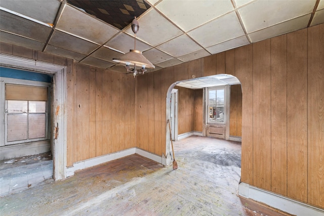 spare room with a paneled ceiling and wood walls