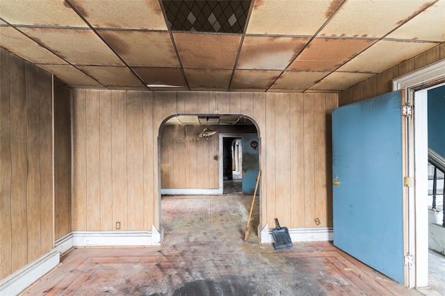 empty room featuring wooden walls and a paneled ceiling