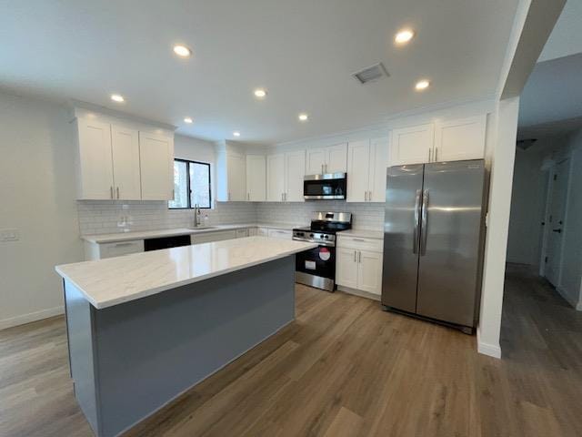 kitchen featuring visible vents, white cabinets, appliances with stainless steel finishes, a center island, and light countertops