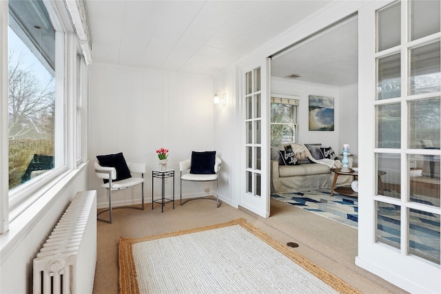 sitting room featuring radiator heating unit, carpet, and french doors