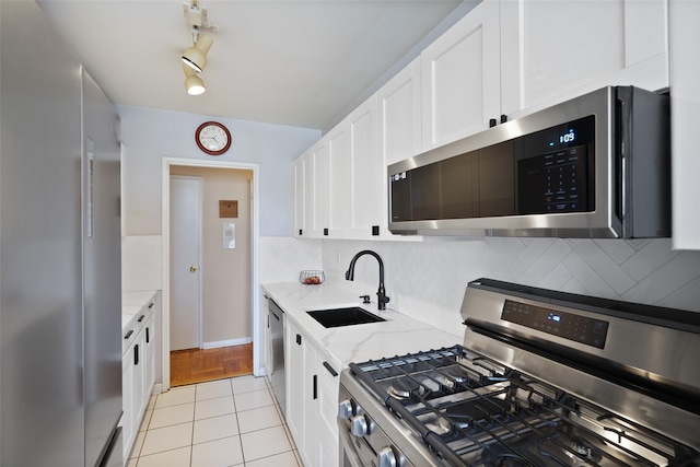 kitchen with a sink, light stone counters, backsplash, stainless steel appliances, and white cabinets