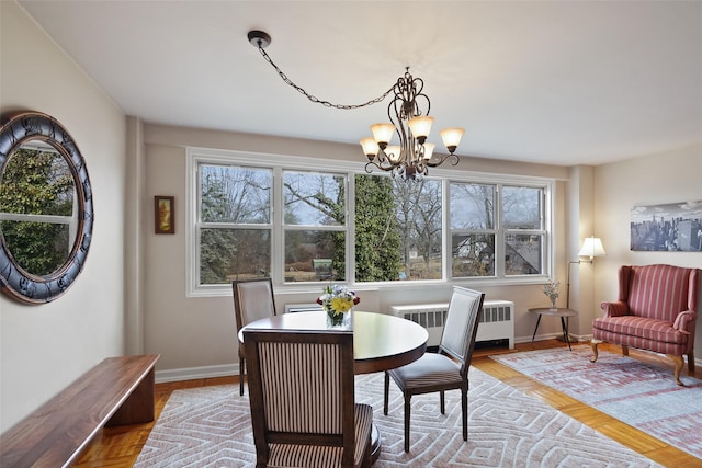 dining space with a chandelier, radiator heating unit, baseboards, and wood finished floors