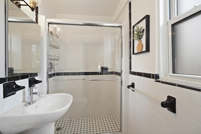 bathroom featuring a sink, tile walls, and a shower stall