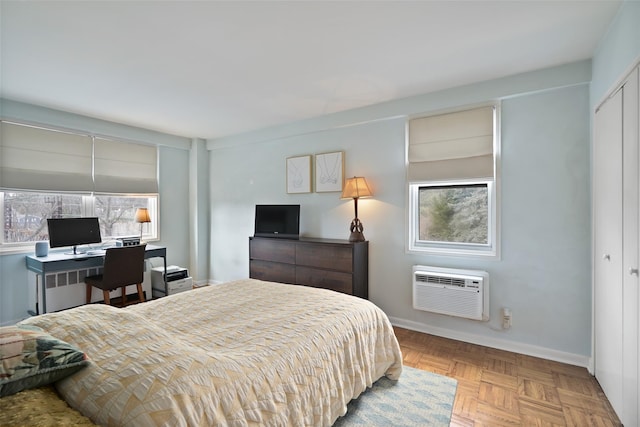 bedroom with a closet, baseboards, radiator, and a wall unit AC