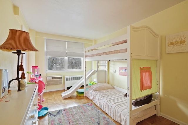 bedroom with a wall mounted air conditioner, baseboards, and radiator heating unit