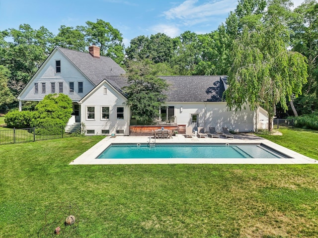 rear view of property with a yard, a fenced in pool, and a patio