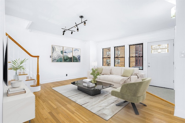 living area with crown molding, stairway, track lighting, wood finished floors, and baseboards