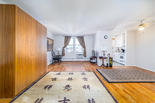 interior space featuring baseboards, ceiling fan, a wall mounted air conditioner, and light wood-style floors