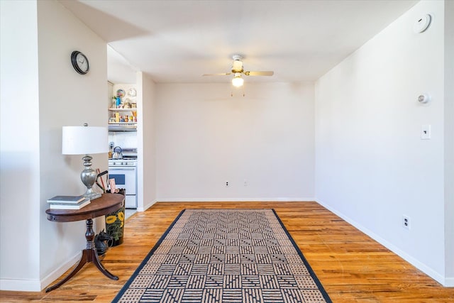 interior space with ceiling fan, baseboards, and wood finished floors