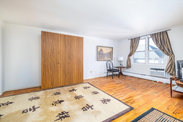 living area with a wall unit AC and wood finished floors