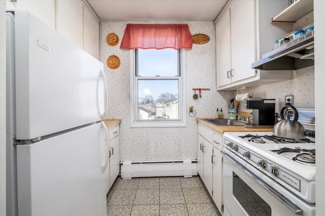 kitchen with white appliances, a baseboard radiator, white cabinetry, and wallpapered walls