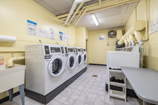 shared laundry area with light tile patterned floors, washer and clothes dryer, and a sink