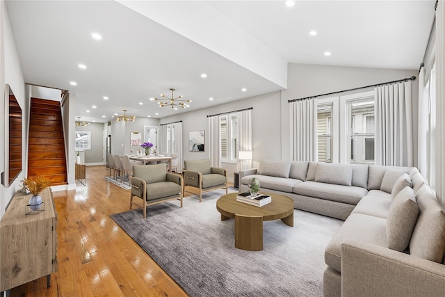 living room with a notable chandelier, light hardwood / wood-style floors, and vaulted ceiling