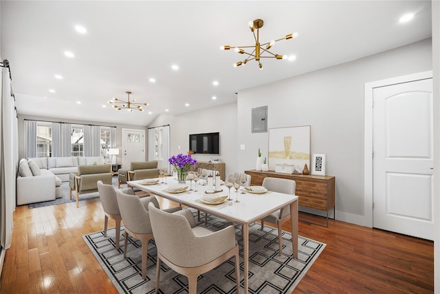 dining room featuring hardwood / wood-style flooring, electric panel, a notable chandelier, and lofted ceiling