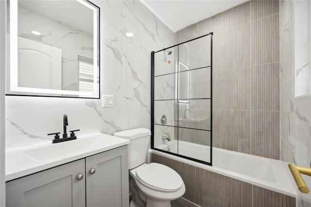 full bathroom with vanity, tile walls, toilet, and tiled shower / bath