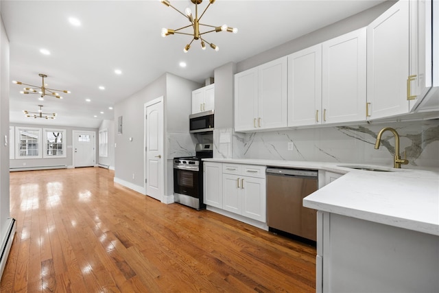 kitchen with white cabinetry, appliances with stainless steel finishes, sink, and a notable chandelier