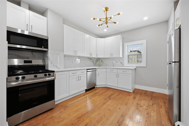 kitchen with light hardwood / wood-style flooring, a notable chandelier, white cabinetry, stainless steel appliances, and tasteful backsplash