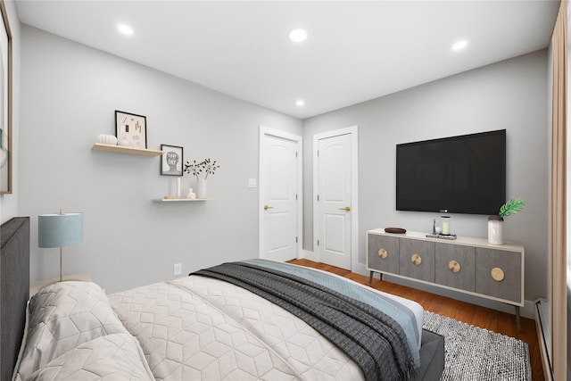 bedroom with a baseboard heating unit and wood-type flooring