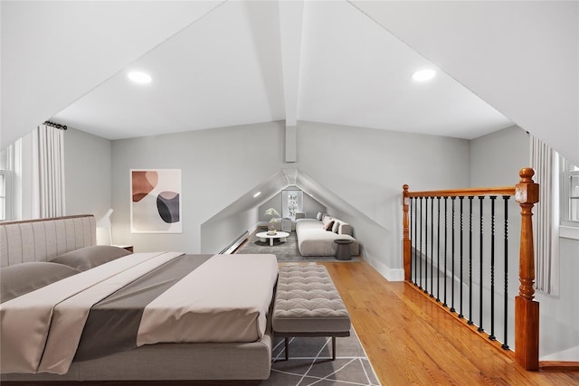 bedroom with a baseboard heating unit, hardwood / wood-style flooring, and vaulted ceiling with beams